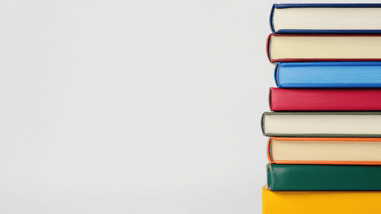 Pila de libros de colores apilados verticalmente sobre fondo blanco