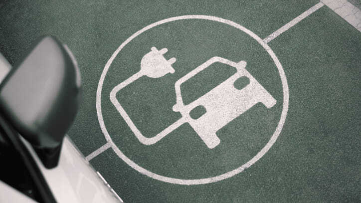 Símbolo pintado en el suelo que indica una plaza de aparcamiento para vehículos eléctricos con punto de carga