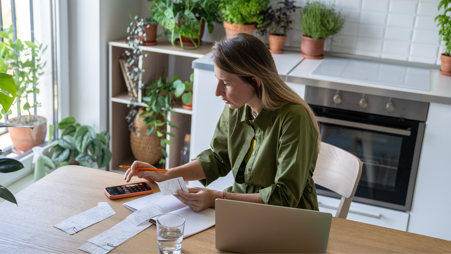 Mujer revisando facturas y usando una calculadora en casa