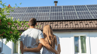 Pareja observando paneles solares en el tejado de su vivienda