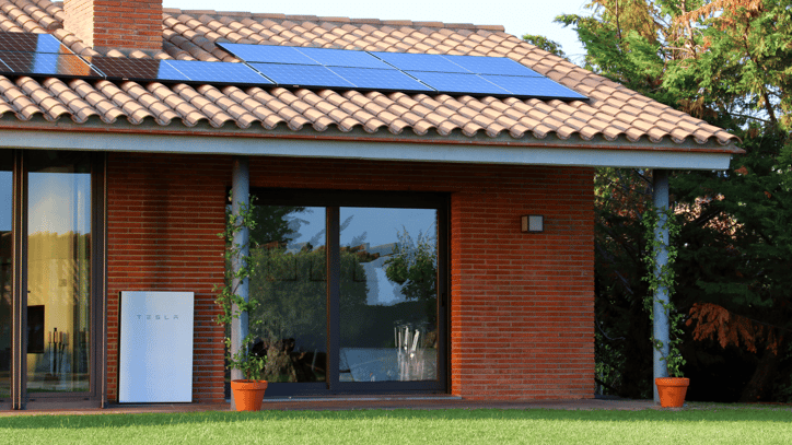 Casa con tejado de tejas equipada con paneles solares y batería Tesla Powerwall instalada en la fachada exterior
