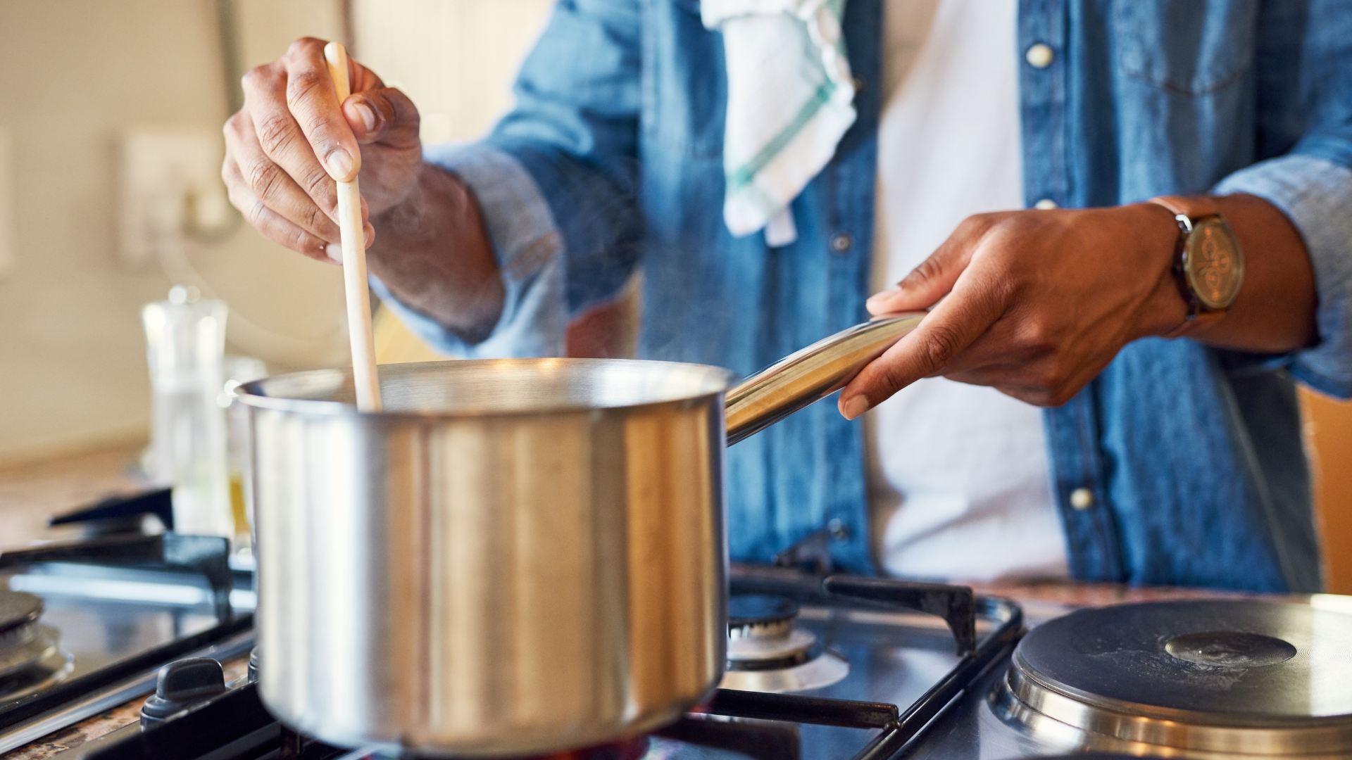 Persona cocinando en una cocina de gas, removiendo una olla sobre los fogones.