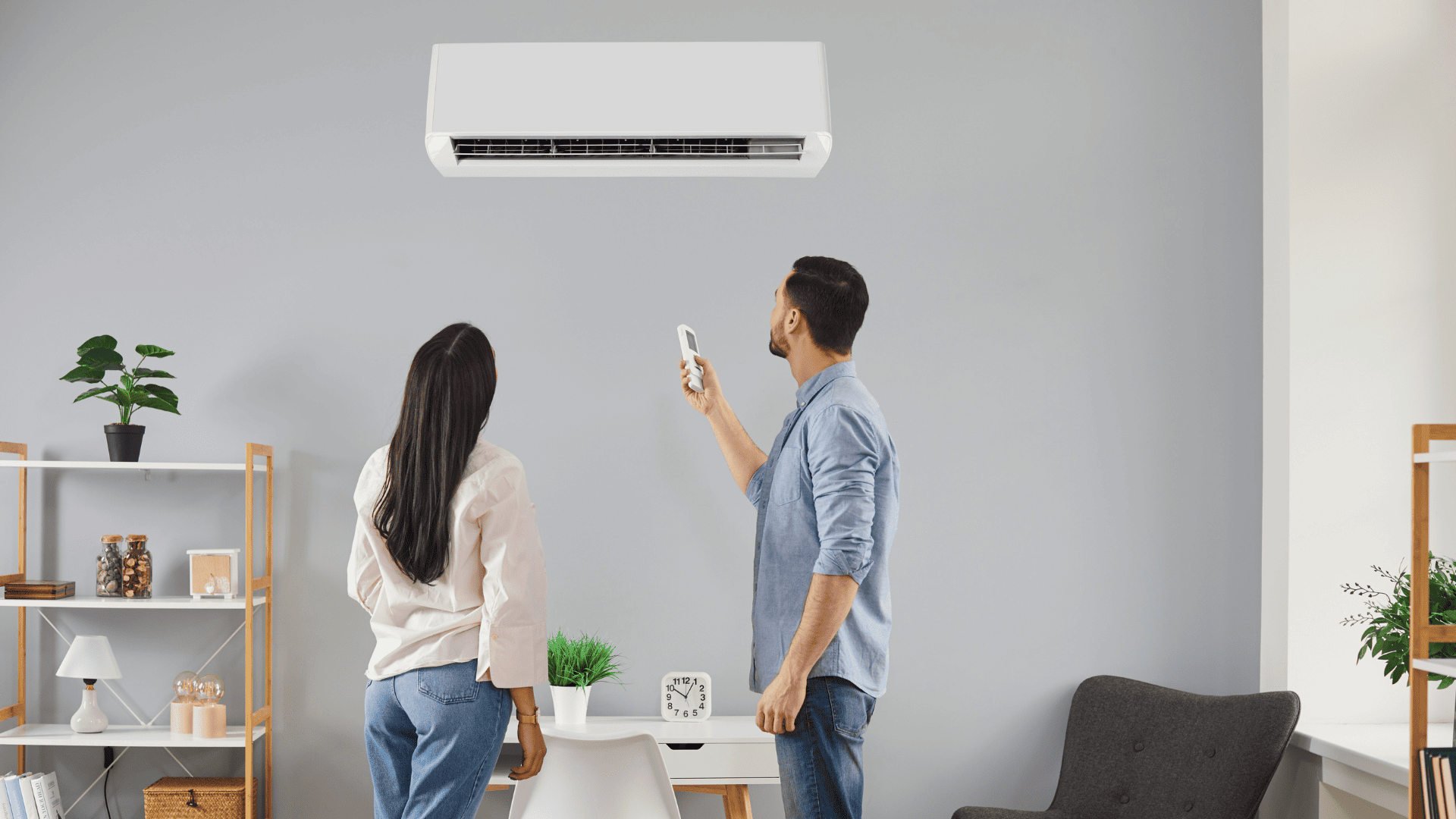 Pareja regulando la temperatura del aire acondicionado con un mando a distancia para mejorar la eficiencia energética en casa.