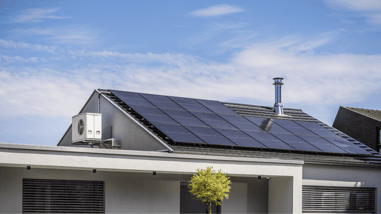 Casa moderna con paneles solares instalados en el tejado inclinado bajo un cielo despejado.