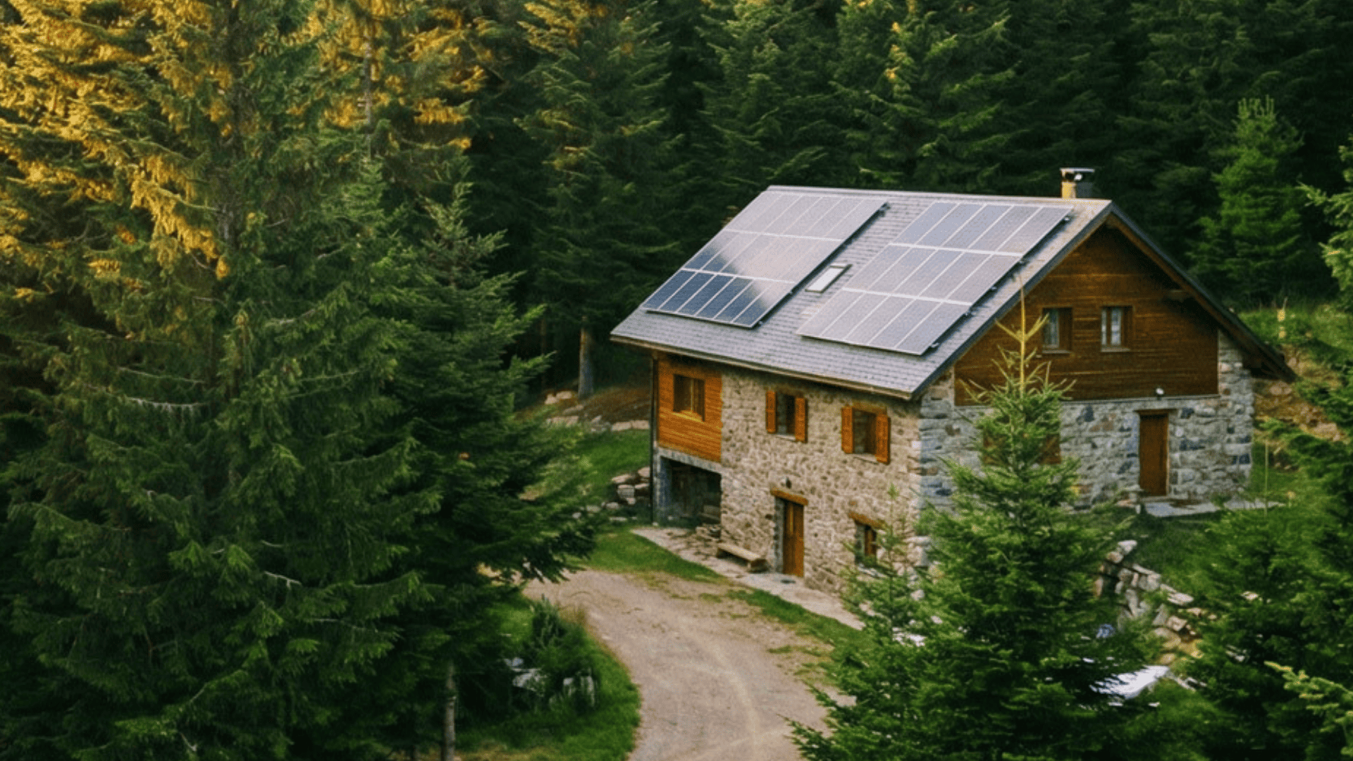 Casa rural de piedra con placas solares en el tejado, rodeada de bosque