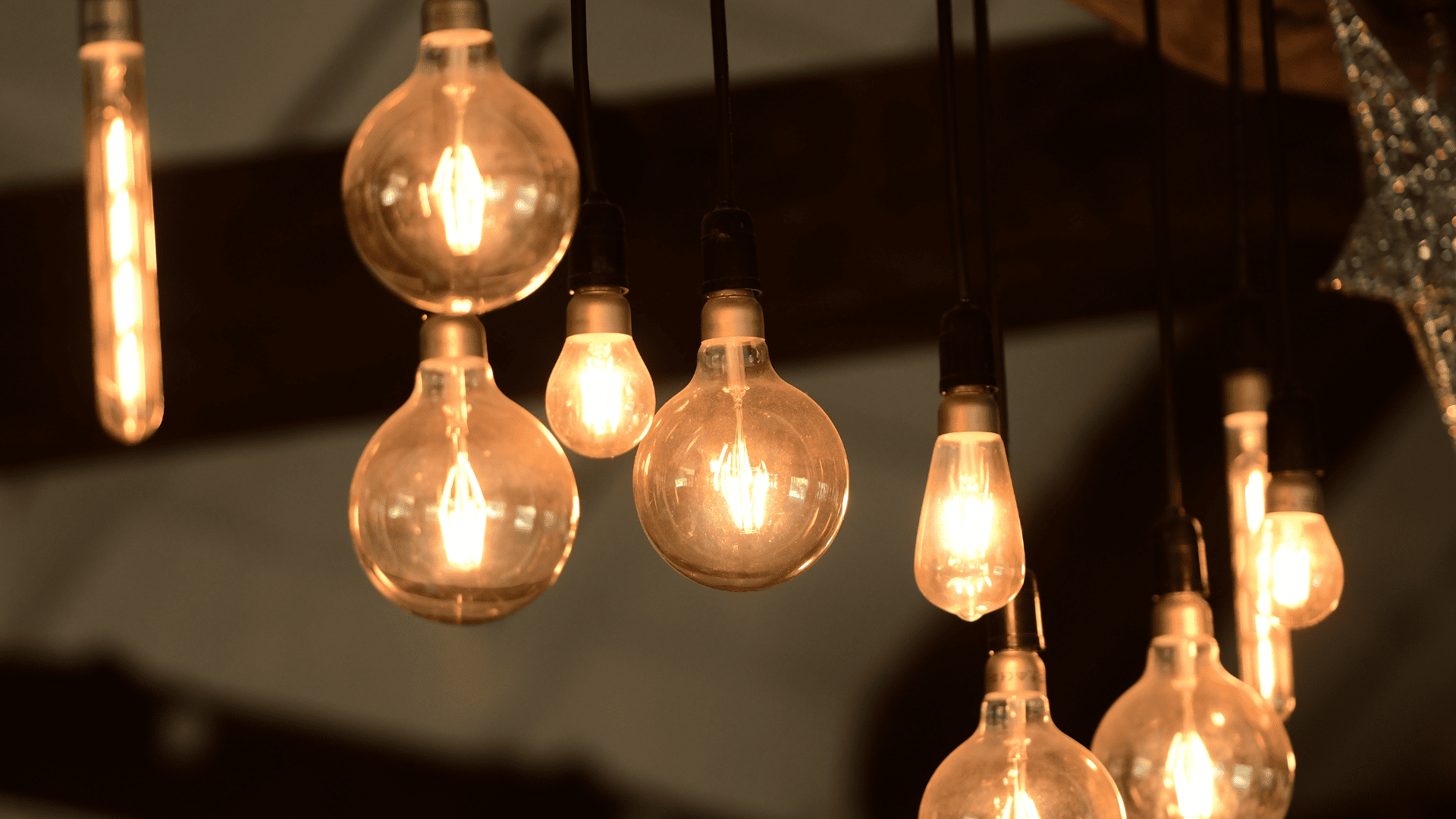 Bombillas encendidas de diferentes formas y tamaños iluminando un espacio interior.