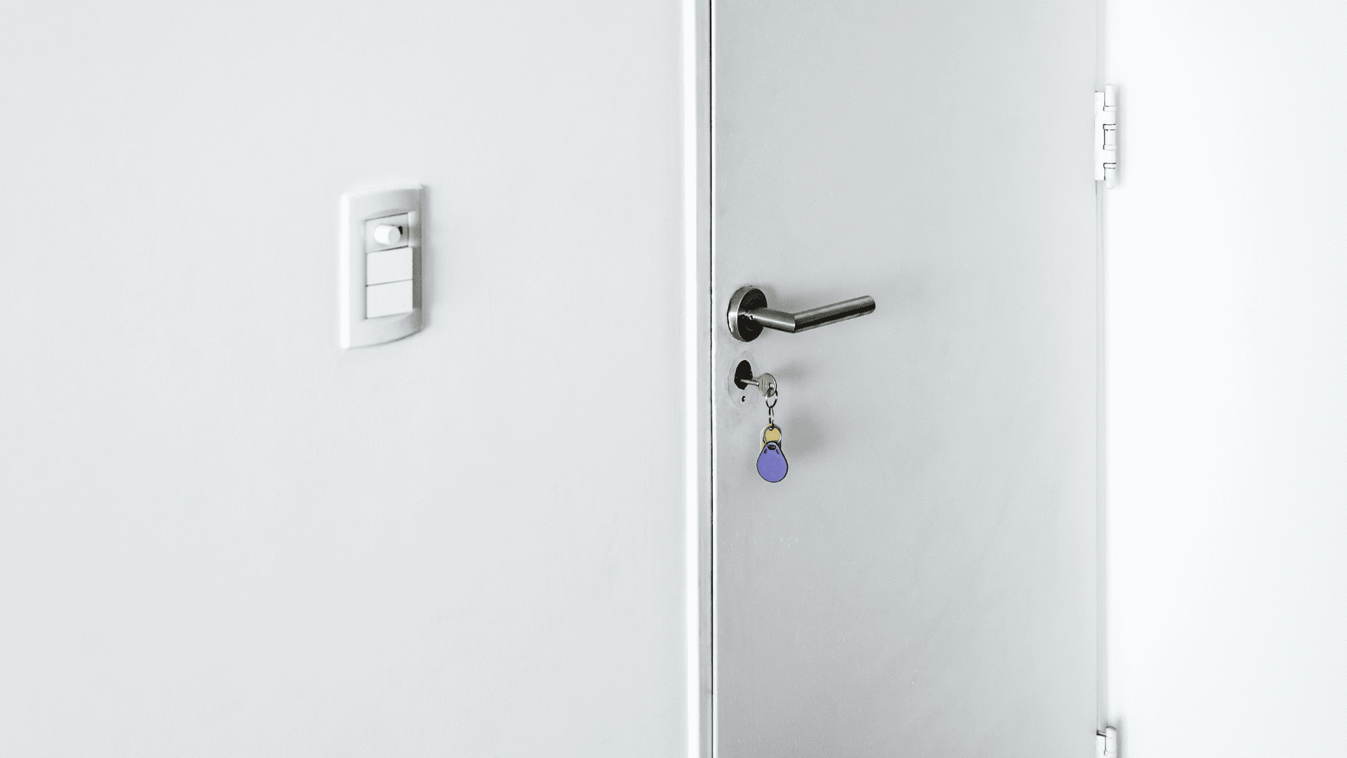 Puerta de entrada blanca con una llave puesta en la cerradura.