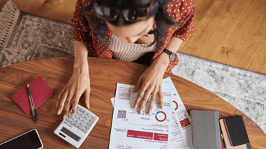 Mujer revisando la factura de la luz y realizando cálculos con una calculadora.