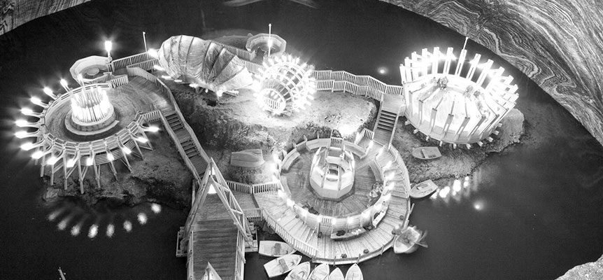Vista aérea en blanco y negro de la mina de sal de Turda, con estructuras iluminadas y pasarelas de madera sobre el agua