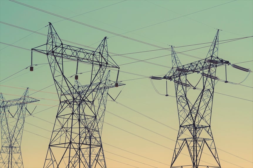 Torres de alta tensión con cables eléctricos al atardecer