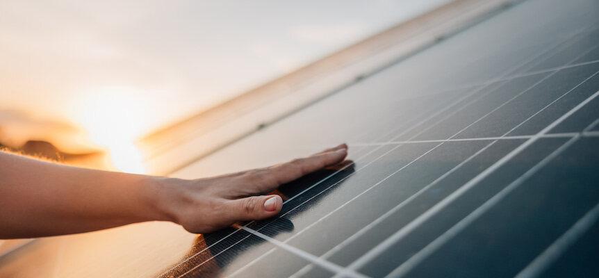 Mano tocando la superficie de una placa solar