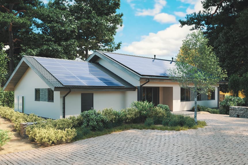 Casa moderna con placas solares en el tejado rodeada de vegetación