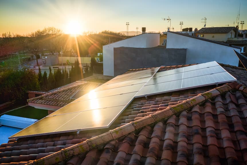 Paneles solares en un tejado con el sol al atardecer
