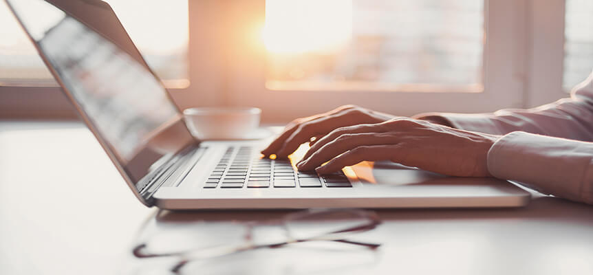 Portátil de perfil con manos escribiendo en el teclado