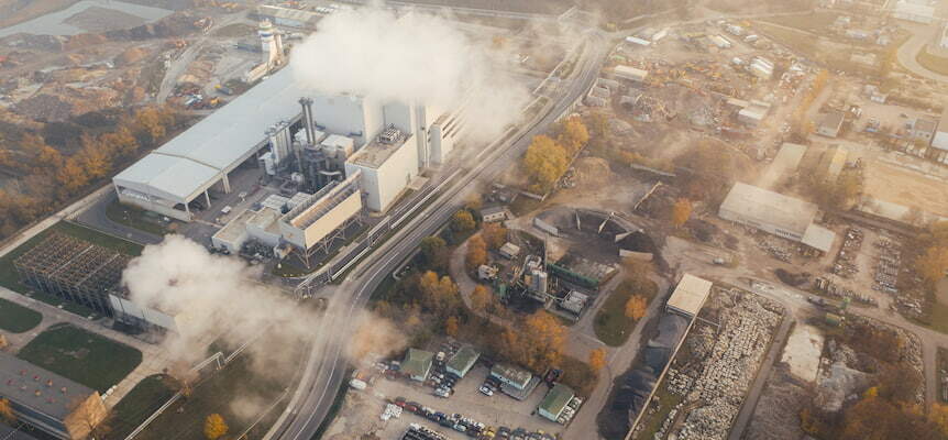 Vista aérea de una central de gas emitiendo humo en un entorno urbano