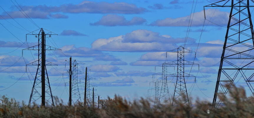 Torres eléctricas bajo un cielo azul con nubes