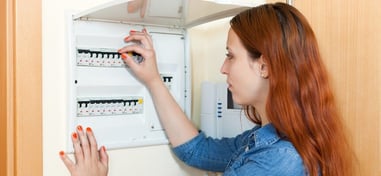 Woman turning a switch on a home electrical panel.