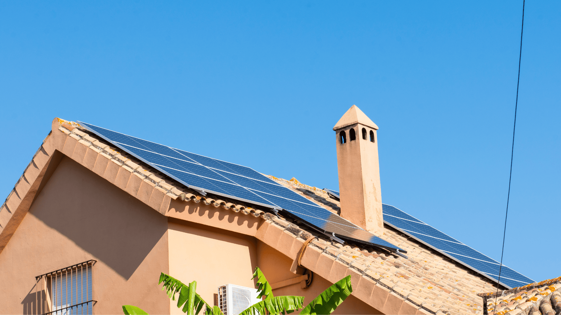 Vivienda con paneles solares instalados en el tejado bajo un cielo azul.
