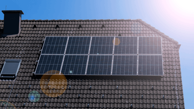Paneles solares instalados en el tejado de una vivienda bajo un cielo azul.