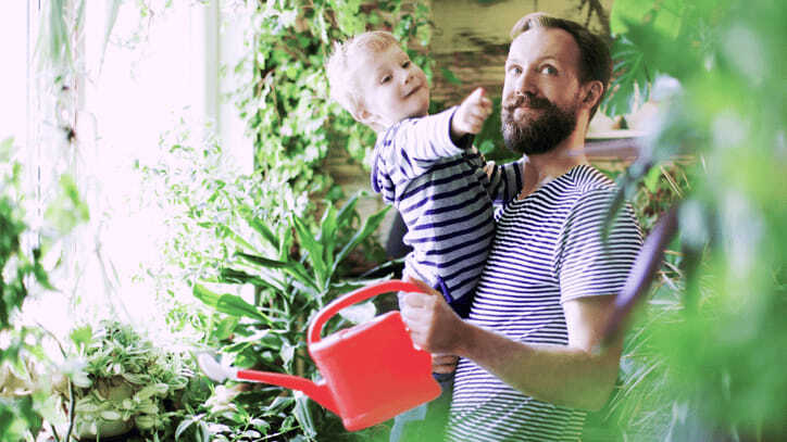 Padre junto a su hijo sosteniendo una regadera