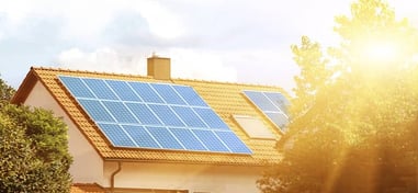 Paneles solares sobre el tejado de una vivienda iluminada por la luz del sol.