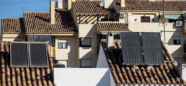 Paneles solares térmicos instalados sobre tejados inclinados en un entorno urbano.
