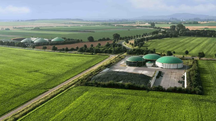 Planta de biogás rodeada de campos agrícolas y zonas verdes.