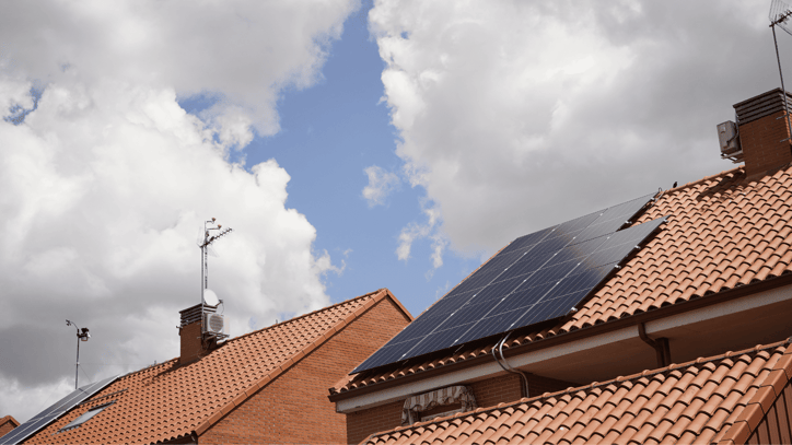 Paneles solares instalados en tejados residenciales bajo un cielo con nubes.