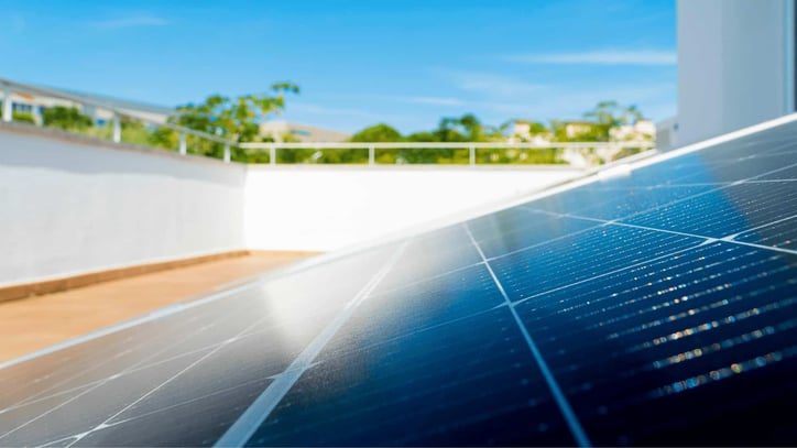 Primer plano de paneles solares instalados en una azotea, captando la luz del sol en un entorno residencial bajo cielo despejado.
