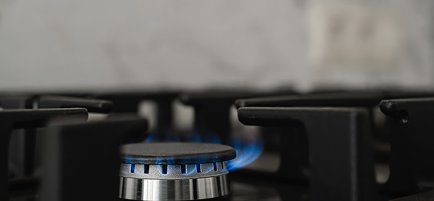 Fogón de cocina encendido con llama azul de gas en primer plano