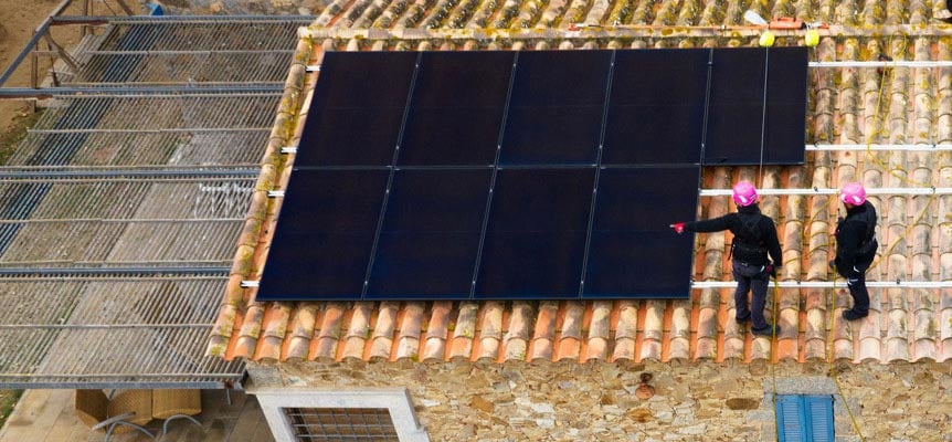 Instaladores colocando paneles solares sobre tejado de tejas