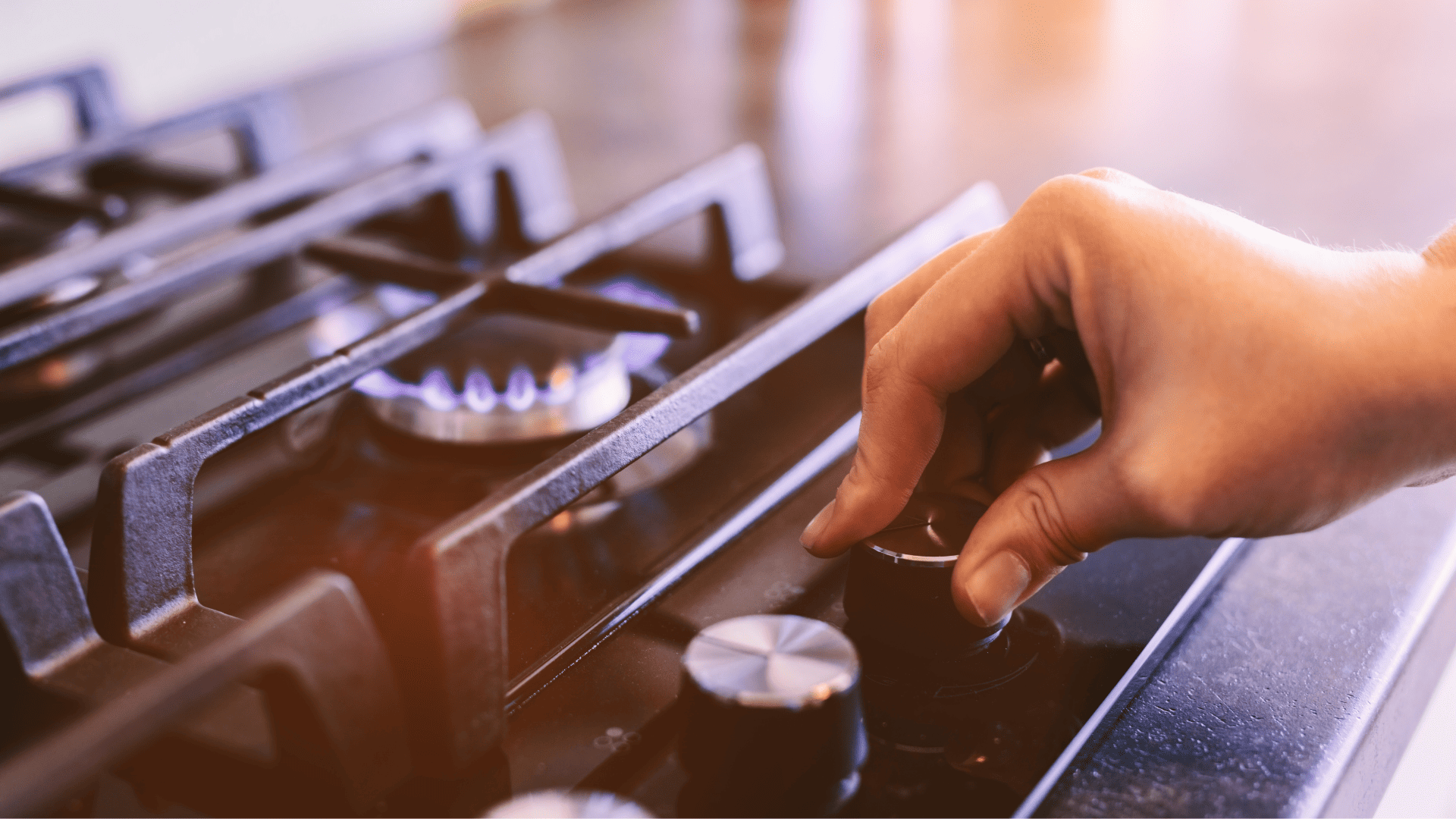 Mano regulando el fuego de una cocina de gas.