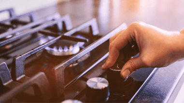 Mano regulando el fuego de una cocina de gas.