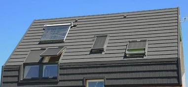 Tejado de vivienda moderna con ventanas abatibles y panel solar térmico.