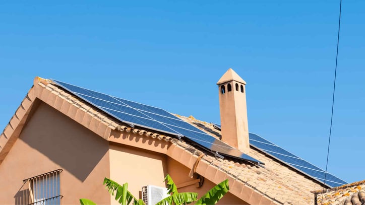 Vivienda con paneles solares instalados en el tejado bajo un cielo azul.
