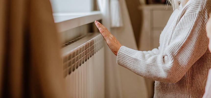 manos de mujer calentándose en un radiador