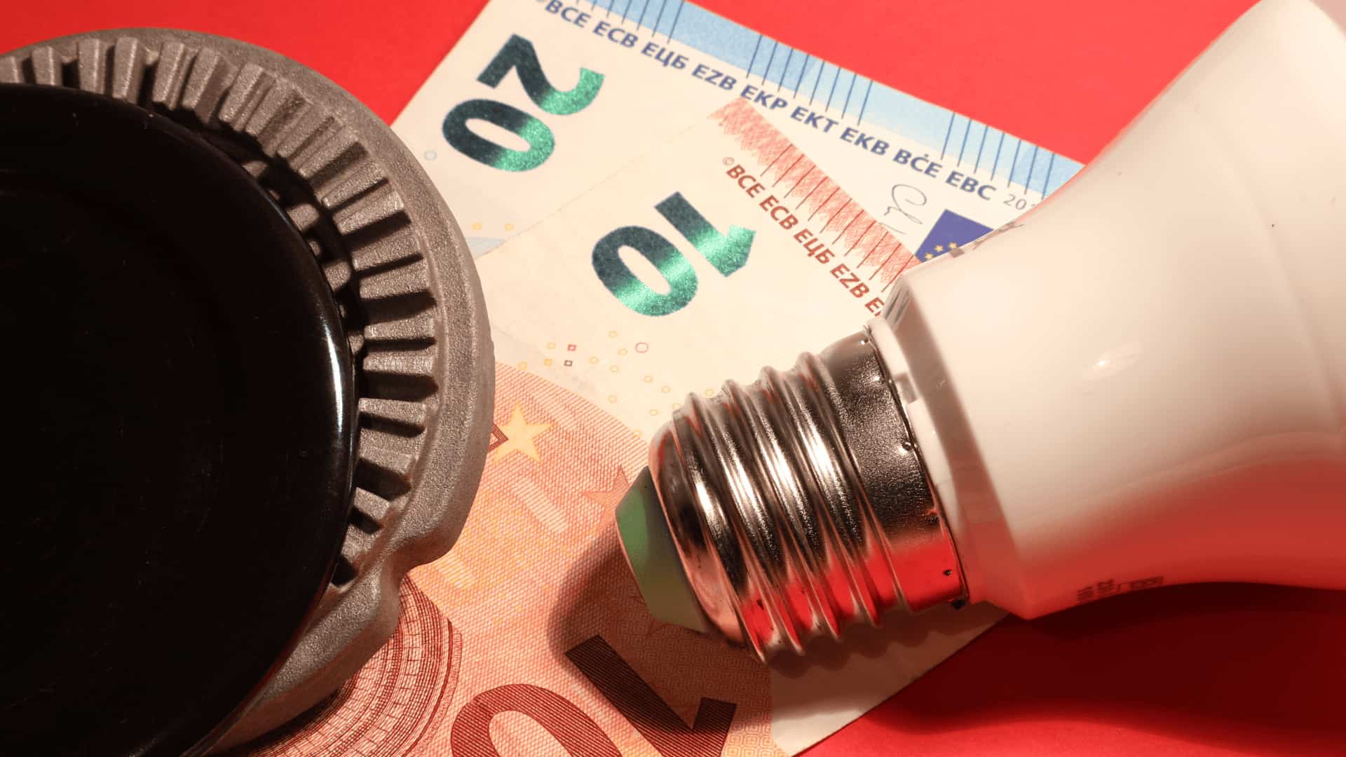 Bombilla LED junto a billetes de euro y un regulador térmico.