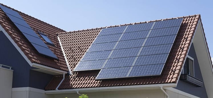 Casa con tejado de tejas rojas y múltiples paneles solares instalados en diferentes secciones del techo