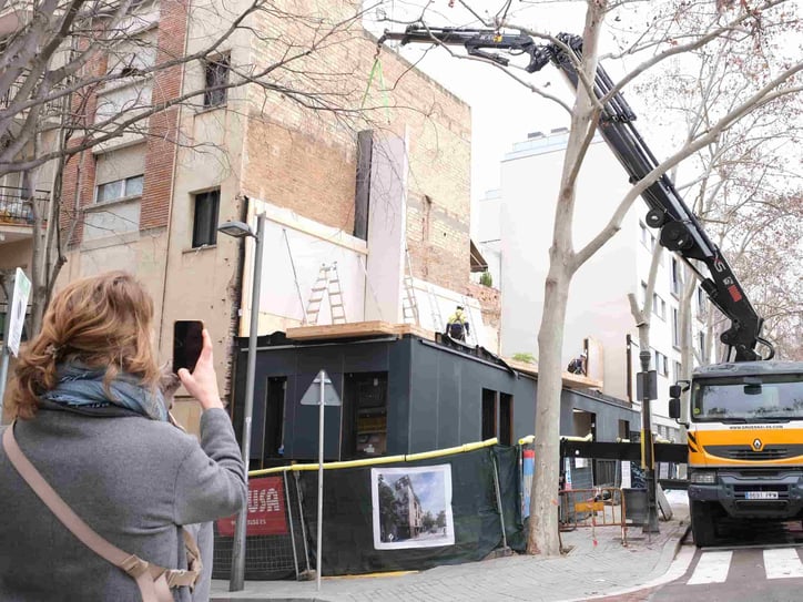 Grúa instalando módulos en una obra urbana.